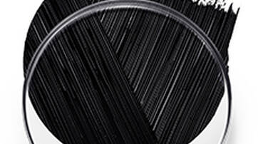 A close-up image of a transparent petri dish containing a yellow gelatin capsule, placed on a monochromatic background featuring brushed black strokes and linear textures.