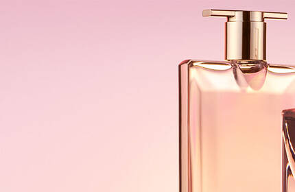 Two elegant perfume bottles are displayed against a soft pink background, showcasing their stylish designs and luxurious appearance.