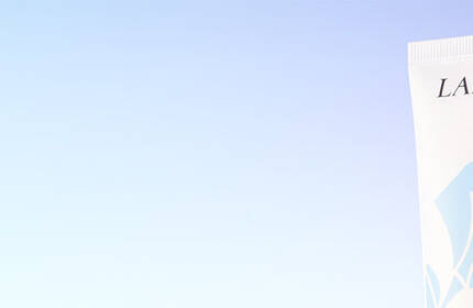 A tube of Lancome Paris product against a gradient background transitioning from light blue to purple.