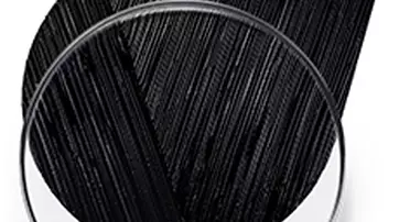 A round dish containing a small golden droplet, with a textured brushstroke of black paint or pigment sweeping across the top.