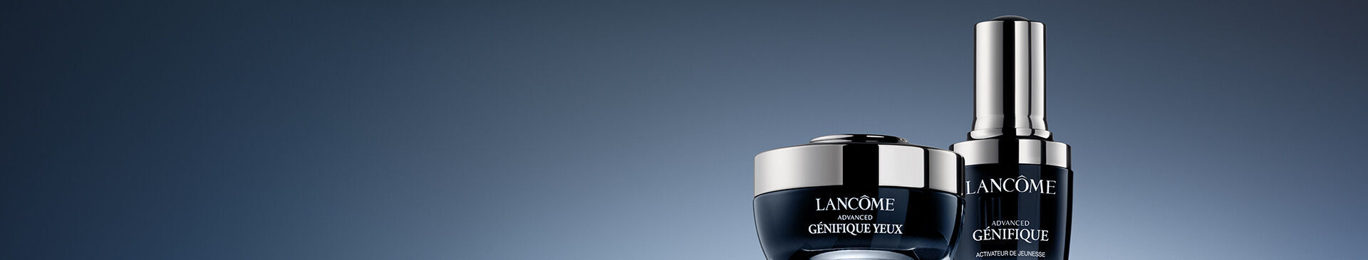 Two Lancome skincare products are displayed against a gradient blue background. The left is a jar labeled "Advanced Genifique Yeux," and the right is a bottle labeled "Advanced Genifique."
