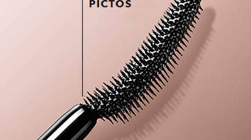 Close-up of a black mascara wand with distinctive bristles, labeled "360 MICRO PICTOS," set against a soft, muted background.
