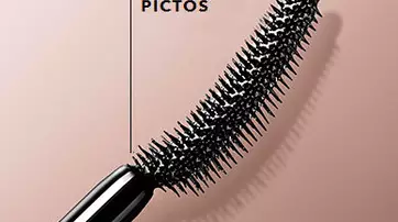 Close-up of a black mascara wand with distinctive bristles, labeled "360 MICRO PICTOS," set against a soft, muted background.