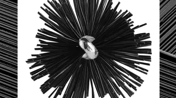 A close-up image of a round, starburst-like object made of black, elongated bristles radiating from a shiny, silver center. The background features a textured, dark pattern.