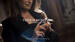 A woman with long, wavy hair in a stylish black outfit holds a perfume bottle, with text overlay that reads "TRESOR MOMENTS WITH PENELOPE CRUZ." The caption below references a memory about the perfume.