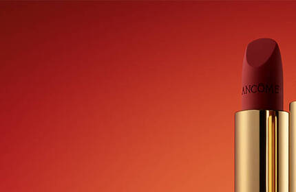Three red lipsticks with gold packaging are lined up against a gradient red background.