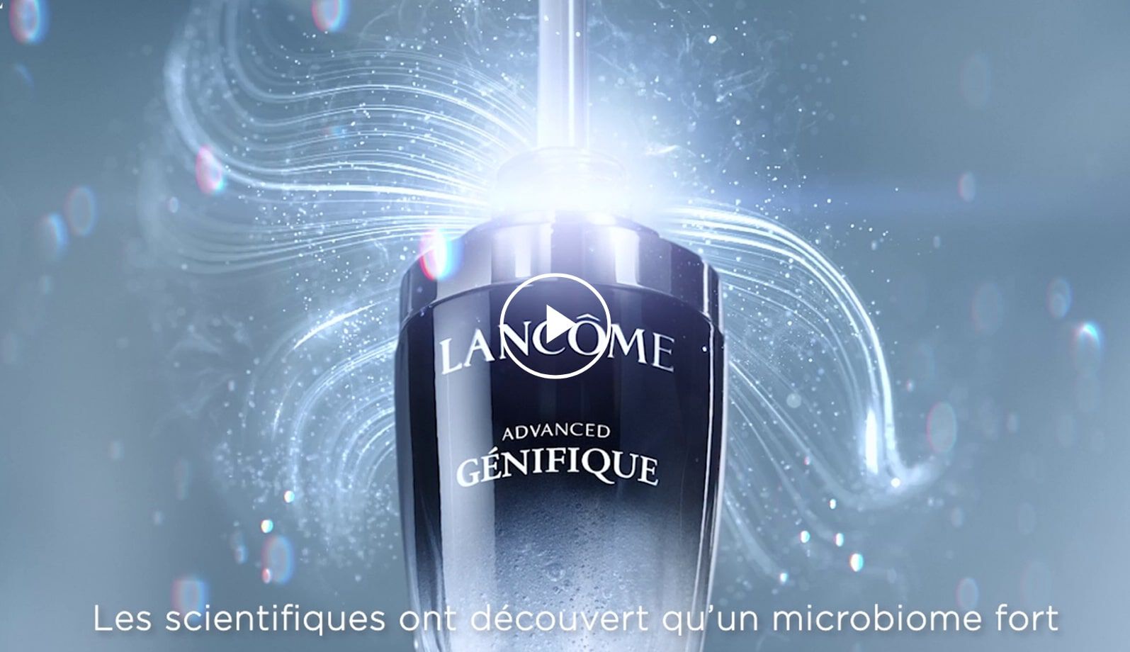 Flacon de serum Lancome Advanced Genifique, mettant en avant un microbiome fort, avec des effets lumineux en arriere-plan.