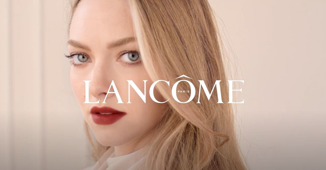 Femme au maquillage sophistique, regard captivant et cheveux longs, avec le logo Lancome en avant-plan.