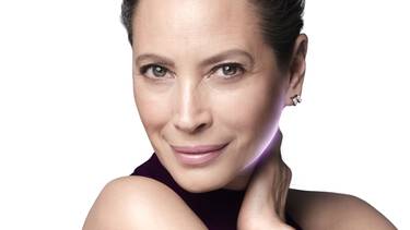 Une personne avec des taches de rousseur applique une creme blanche sur sa joue.