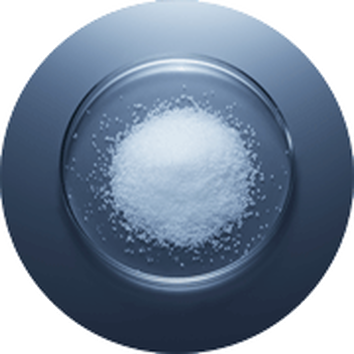 Un plat en verre contenant une petite quantite de sel blanc fin sur un fond bleu fonce.