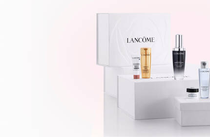 A display of Lancome skincare products, including various bottles and jars, arranged on white boxes with a minimalistic background featuring the Lancome logo.