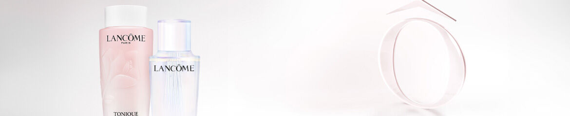 Two bottles of Lancome skincare products are displayed on a light background. The left bottle is labeled "Toniques" and has a soft pink hue, while the right bottle is clear and has a sleek design. A minimalist geometric shape is also present in the image.