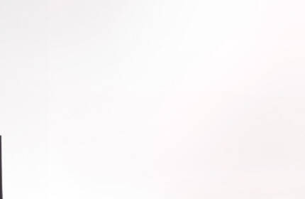 Three Lancome lipstick tubes in various shades, with one applicator prominently displayed, set against a light background featuring a circular design.