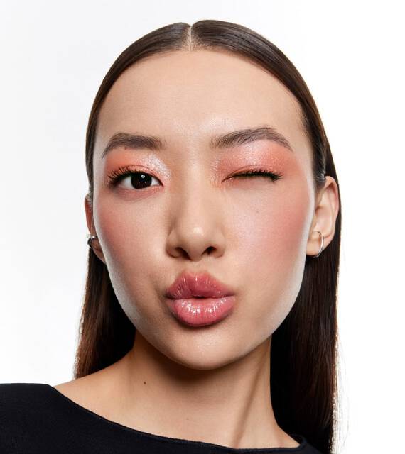 Femme faisant un clin d’oeil et un bisou avec un maquillage corail.