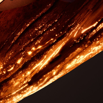 Texture en gros plan d'une surface brillante et doree, evoquant un metal chauffe ou une roche fondue.