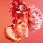 Flacon de parfum Lancome Idole entoure de baies rouges, d'une pivoine rose et d'une tranche
            d'agrume sur un fond corail.