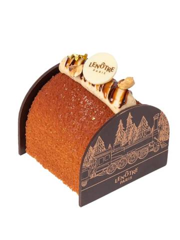 Une petite buche elegante avec un glacage marron brillant, decoree de noix et d'accents en chocolat sur les cotes.