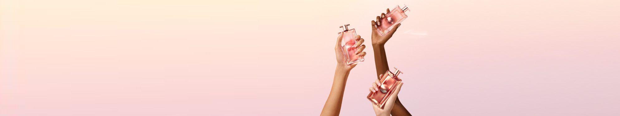 Three hands, two light and one darker skin tone, hold up elegant pink perfume bottles against a soft gradient background.