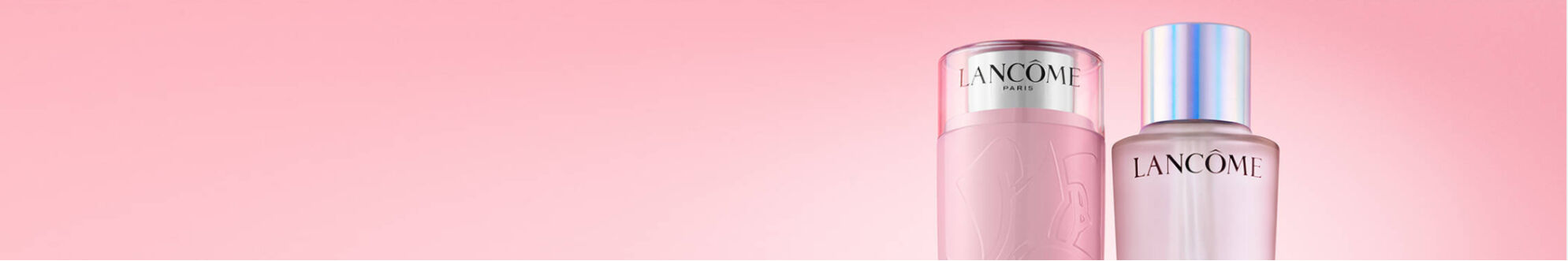 Two elegant skincare bottles from Lancome are displayed against a soft pink background. The left bottle is a luxurious pink toner, while the right bottle is a lightweight serum.