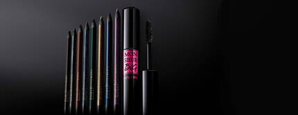 A collection of colorful eyeliners and a mascara, displayed against a dark background, highlighting the products' sleek packaging.