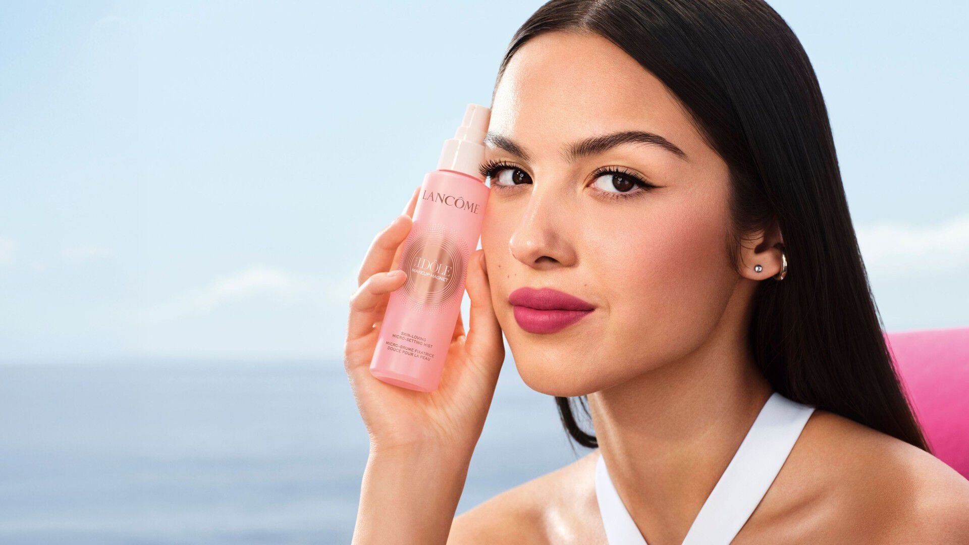 Model holding Lancôme Skin Idole Magnet Spray mist by the sea.