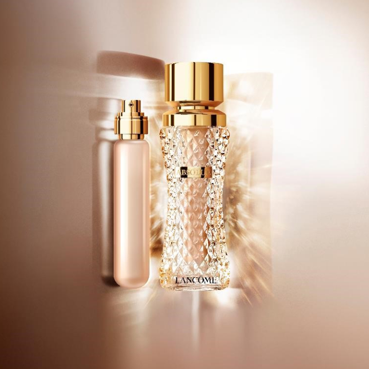 Flacon de parfum Lancôme, élégant, en verre transparent avec un capuchon doré, sur un fond lumineux.