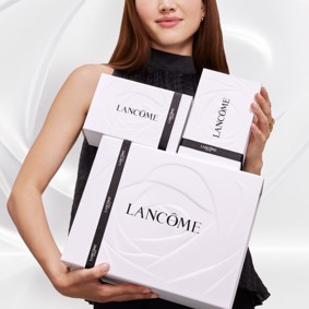 Flacon de parfum élégant, transparent avec une teinte rosée et un capuchon en métal, posé sur un fond blanc.